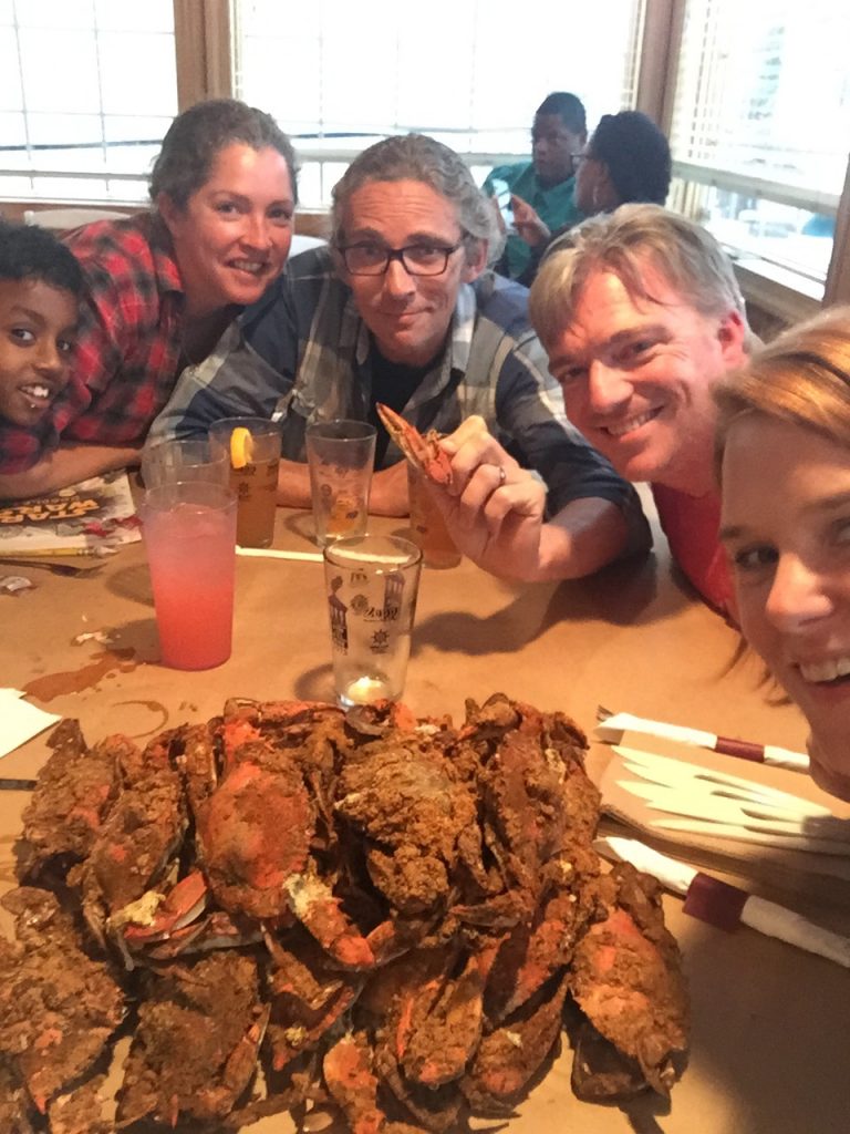 Mathew, Kara, Drummer, Erik, and Slinky around a table piled high Maryland crabs